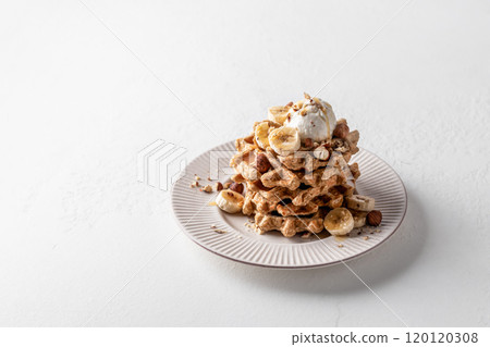 Homemade waffles stack with ice cream, bananas and nuts on white plate isolated on white background, text space Homemade waffles stack with ice cream, bananas and nuts on white plate isolated on white background, text space 120120308