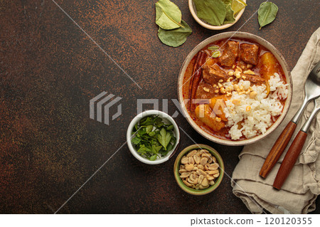 Delicious massaman curry with beef, potatoes, rice, and peanuts is served in bowl top view, Thai cuisine, space for text Delicious massaman curry with beef, potatoes, rice, and peanuts is served in bowl top view, Thai cuisine, space for text 120120355