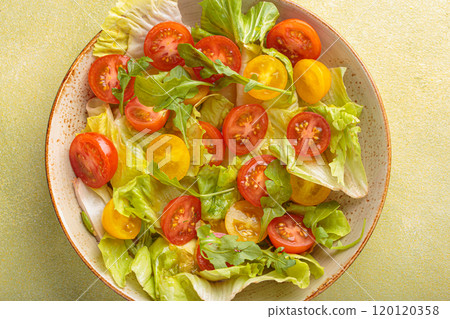Fresh salad with lettuce, cherry red and yellow tomatoes, and arugula in a bowl top view, dieting and healthy eating Fresh salad with lettuce, cherry red and yellow tomatoes, and arugula in a bowl top view, dieting and healthy eating 120120358