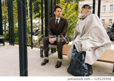 Process chatting of empathetic businessman in suit and old homeless man sitting on bench, representing growing gap between rich and poor in society. Concept of social issues and economic disparity. Process chatting of empathetic businessman in suit and old homeless man sitting on bench, representing growing gap between rich and poor in society. Concept of social issues and economic disparity. 120120506