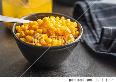 Canned sweet corn in bowl on black kitchen table. 120121002