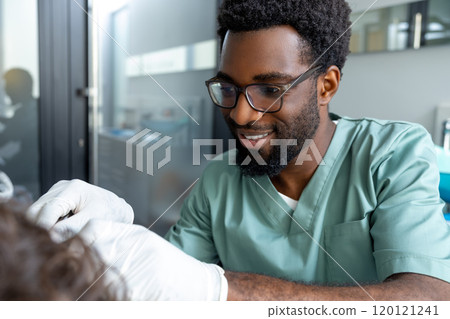 Orthodontist conducting dental checkup in modern clinic examining patient's teeth 120121241