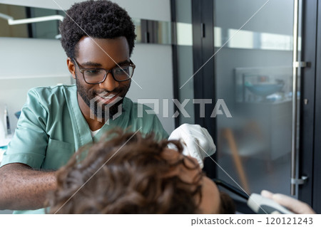Orthodontist conducting dental checkup in modern clinic examining patient's teeth Orthodontist conducting dental checkup in modern clinic examining patient's teeth 120121243
