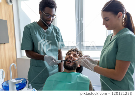 Male dentist examining patient’s teeth during checkup in dental office using orthodontic tools Male dentist examining patient’s teeth during checkup in dental office using orthodontic tools 120121258