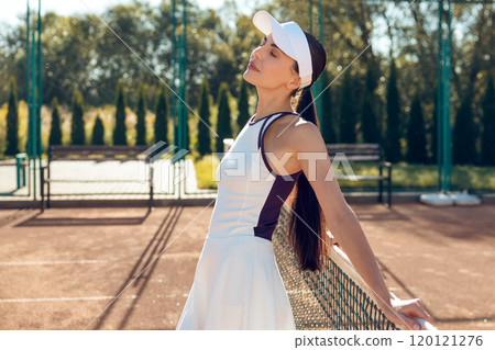 Beautiful young woman on the tennis courts looking contented and smiling Beautiful young woman on the tennis courts looking contented and smiling 120121276
