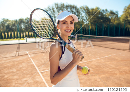 Confident female tennis player with a racket in hands looking excited Confident female tennis player with a racket in hands looking excited 120121293