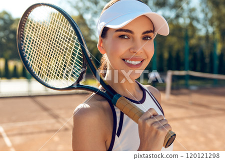Confident female tennis player with a racket in hands looking excited Confident female tennis player with a racket in hands looking excited 120121298
