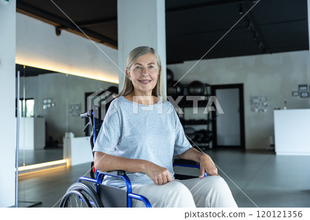 Blonde mature woman sitting in a wheel-chair and looking positive Blonde mature woman sitting in a wheel-chair and looking positive 120121356