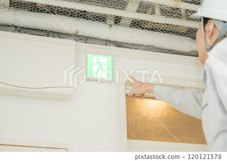 一名身穿消防設備工作服的婦女檢查疏散導燈 120121578