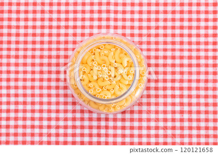 Uncooked Chifferi Rigati Pasta in Glass Jar on Checkered Red Towel Uncooked Chifferi Rigati Pasta in Glass Jar on Checkered Red Towel 120121658