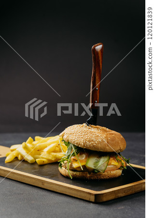 Gourmet burger with arugula, egg, and fresh vegetables served with crispy golden fries on board 120121839