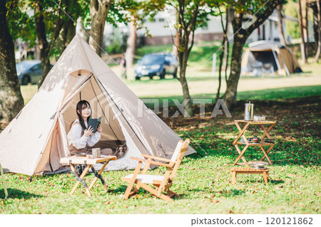 Young woman enjoying reading in a tent 120121862