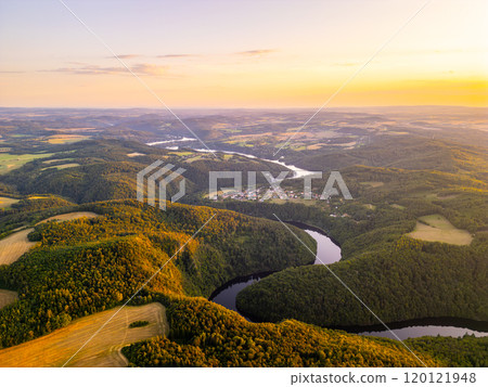 The warm glow of sunset blankets the rolling hills and winding Vltava River in Czechia. This tranquil moment captures nature's beauty and the peaceful flow of water through a lush valley. The warm glow of sunset blankets the rolling hills and winding Vltava River in Czechia. This tranquil moment captures nature's beauty and the peaceful flow of water through a lush valley. 120121948