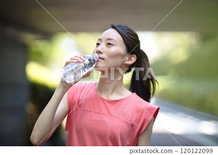 Young woman in sportswear drinking water from a plastic bottle Young woman in sportswear drinking water from a plastic bottle 120122099