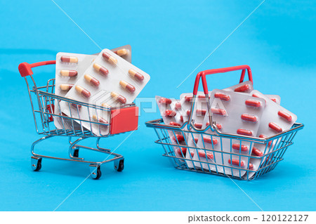 Pills and Capsules in Shopping Cart on Blue Background 120122127