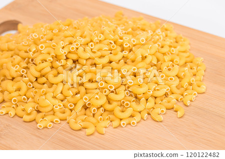 A Heap of Uncooked Chifferi Rigati Pasta on Wooden Kitchen Board A Heap of Uncooked Chifferi Rigati Pasta on Wooden Kitchen Board 120122482