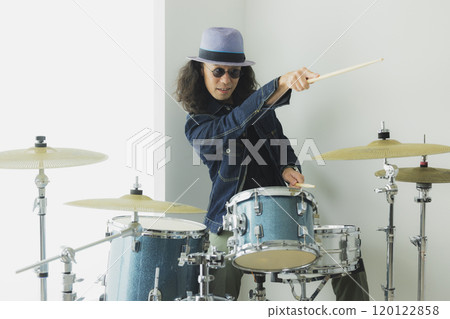 A man with long hair playing the drums 120122858