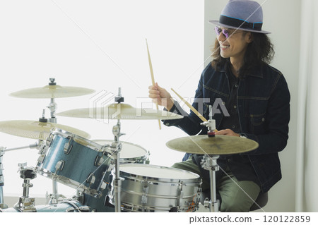 A man with long hair playing the drums A man with long hair playing the drums 120122859