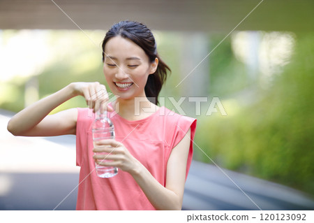 穿著運動服的年輕女子用塑膠瓶喝水 120123092