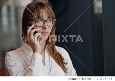 A Professional Woman is Engaged in a Business Phone Conversation while managing her tasks 120123253