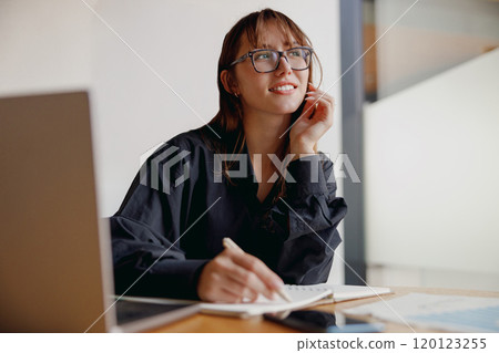 A Thoughtful Woman Dressed in a Black Shirt Diligently Working on a Project Assignment 120123255