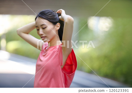 一位穿著運動服的年輕女子站在綠樹叢中 一位穿著運動服的年輕女子站在綠樹叢中 120123391