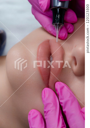 A beautician does permanent lip makeup on a woman. Tattooing in a beauty salon. 120123800