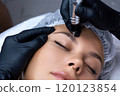 A beautician does permanent eyeliner makeup on a woman. Tattooing in a beauty salon. 120123854