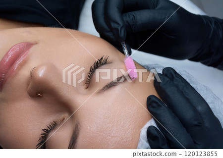 A beautician brushes the eyebrows of a client. Eyebrow care procedure in a salon. 120123855