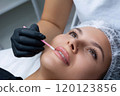 A beautician performs a lip care procedure for a woman. A salon treatment, self-care concept. 120123856