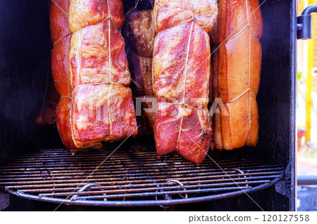 Cooking tradition various cuts of in smoker, bacon hung from hooks racks to produce delicious meal in smokehouse 120127558