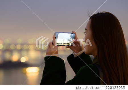 A woman taking a photo of the winter night view of Odaiba with her smartphone 120128035