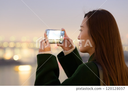 A woman taking a photo of the winter night view of Odaiba with her smartphone A woman taking a photo of the winter night view of Odaiba with her smartphone 120128037