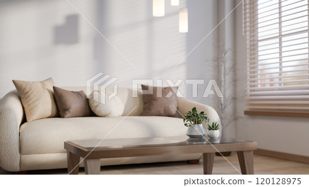 A minimal living room features a white couch with brown pillows and a coffee table in the window. A minimal living room features a white couch with brown pillows and a coffee table in the window. 120128975