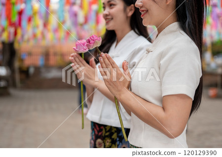 A close-up of two beautiful Asian women praying at a temple during a traditional festival. A close-up of two beautiful Asian women praying at a temple during a traditional festival. 120129390