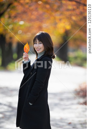 Smiling young woman against the background of autumn leaves of Sakuranomiya Park in Miyakojima, Osaka City, Osaka Prefecture 120130110
