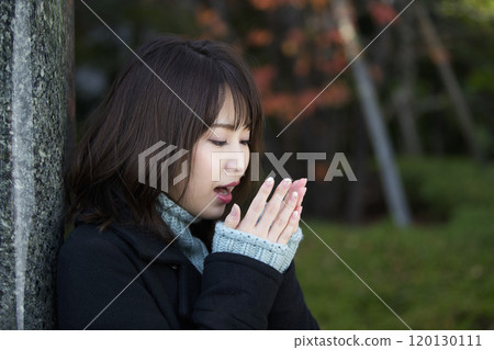A young woman warming her hands with her breath in Sakuranomiya Park in Miyakojima-ku, Osaka City, Osaka Prefecture 120130111