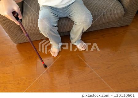 A person sitting on a sofa holding a cane 120130601