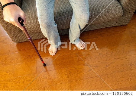 A person using a cane to get up from a sofa 120130602
