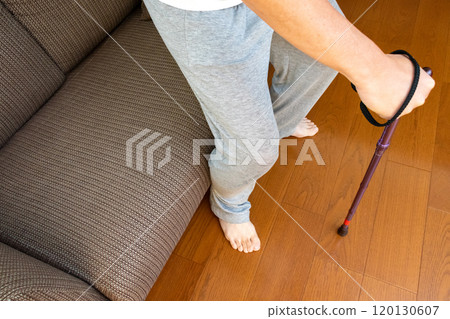 A person using a cane to get up from a sofa A person using a cane to get up from a sofa 120130607
