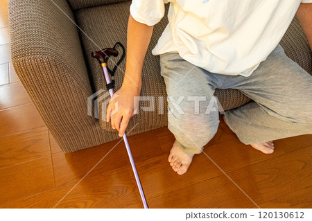 A man sitting on a sofa with a cane beside him A man sitting on a sofa with a cane beside him 120130612