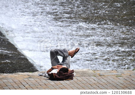 Man lying on the riverside 120130688