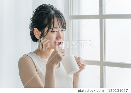 Asian woman having pain in her molars while brushing her teeth Asian woman having pain in her molars while brushing her teeth 120131037