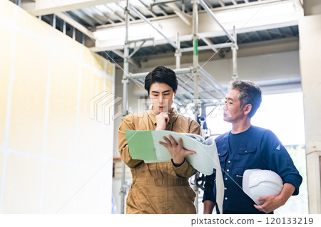 Carpenter and worker consulting at a construction site 120133219