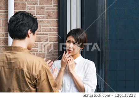 A female resident is frightened as the contractor explains the situation to her at the entrance. 120133228