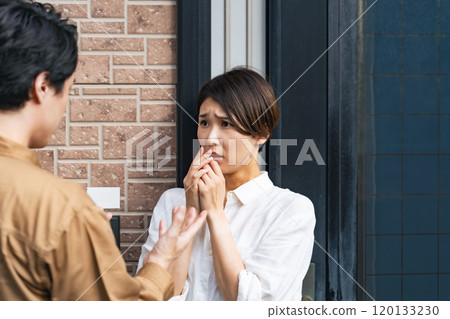 A female resident is frightened as the contractor explains the situation to her at the entrance. 120133230