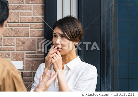 A female resident is frightened as the contractor explains the situation to her at the entrance. 120133231