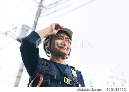 Senior worker standing in front of a utility pole Senior worker standing in front of a utility pole 120133252
