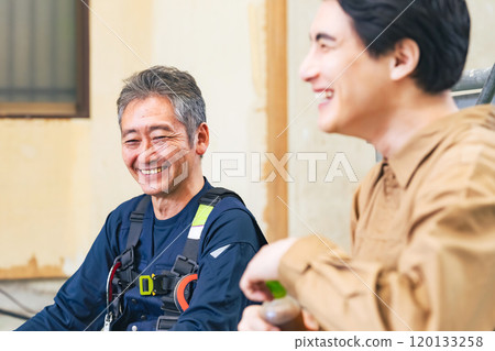 Carpenter and worker chatting at a construction site 120133258