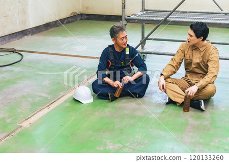 Carpenter and worker taking a break at a construction site 120133260